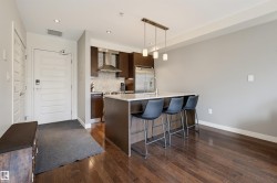 Open-concept kitchen and living area featuring wood-finish flooring, recessed lighting, and a kitchen island with stone countertop - 