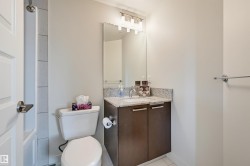 Bathroom featuring a contemporary vanity with a stone-finish countertop, undermount sink, and dark wood-finish cabinetry - 