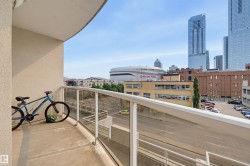 Private balcony featuring a concrete floor, glass railing, and urban landscape with distant high-rise buildings and stadium - 