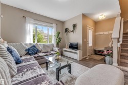 Bright living area featuring large windows, wood-finish flooring, a built-in entry bench, and carpeted stairs - 