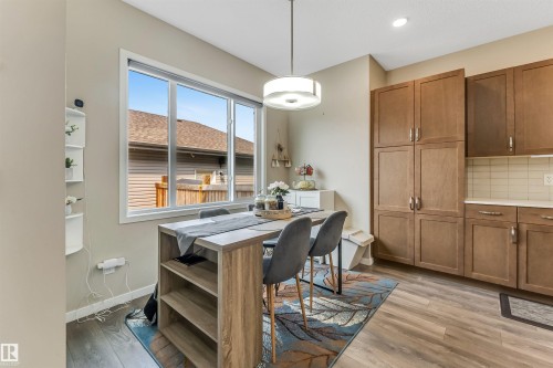 Open-concept kitchen and dining area featuring wood-finish flooring, ample cabinetry with brushed nickel hardware, and a subway tile backsplash - 1514 26 Avenue Nw, Edmonton, AB - Indoor Photo Showing Dining Room