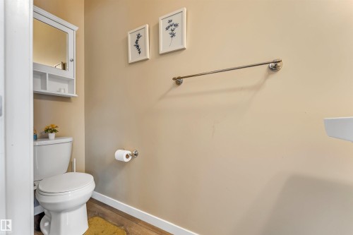 Bathroom featuring wood-finish flooring, a white toilet, and a wall-mounted white medicine cabinet with mirrored door - 1514 26 Avenue Nw, Edmonton, AB - Indoor Photo Showing Bathroom
