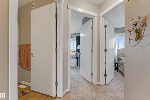 Interior hallway featuring white paneled doors with horizontal detailing, light beige walls, and light-colored carpeting - 1514 26 Avenue Nw, Edmonton, AB - Indoor Photo Showing Other Room