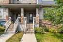 Townhome exterior featuring stacked stone accents, light gray siding, and a covered front porch with white railings - 1514 26 Avenue Nw, Edmonton, AB  - Outdoor 