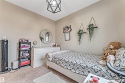Carpeted room featuring a white dresser, a wall-mounted round mirror, and a geometric semi-flush mount light fixture - 