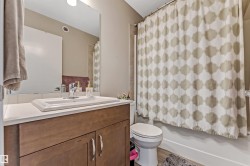 Bathroom vanity featuring a rectangular sink, chrome faucet, and wood-finish cabinetry - 