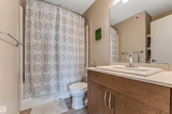 Bathroom featuring a wood-finish vanity with a light-toned countertop, an integrated sink, and a chrome faucet - 