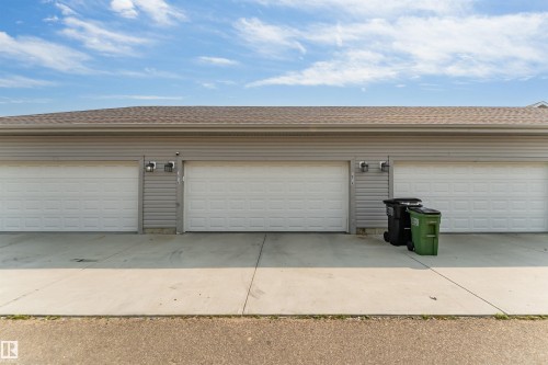 Three white garage doors with textured panels, light gray horizontal siding, and a brown shingle roof - 1514 26 Avenue Nw, Edmonton, AB - Outdoor