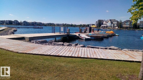 Lakeside boardwalk leading to a dock structure with adjacent residential properties - 1839 80 Street Sw, Edmonton, AB 