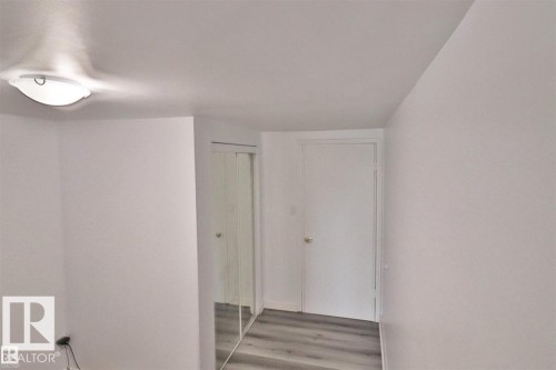 White walls with flush-mount lighting, wood-finish flooring, and mirrored closet doors - 98 Willow Park Estates, Leduc, AB 