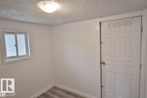 Recessed window, white trim, paneled door, flush mount ceiling light, and wood-finish flooring - 98 Willow Park Estates, Leduc, AB 