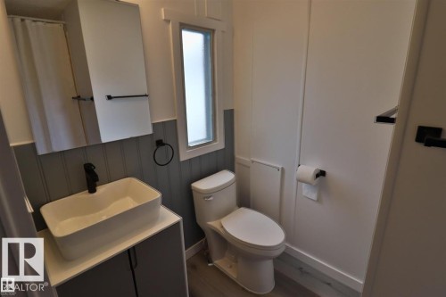 Vanity with a rectangular vessel sink, matte black faucet, and storage cabinetry - 98 Willow Park Estates, Leduc, AB 
