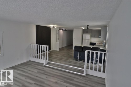 Wood-finish flooring throughout, white painted walls, and a white balustrade - 98 Willow Park Estates, Leduc, AB 