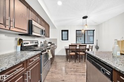 Kitchen featuring stainless steel appliances, dark wood cabinetry, and speckled countertops - 
