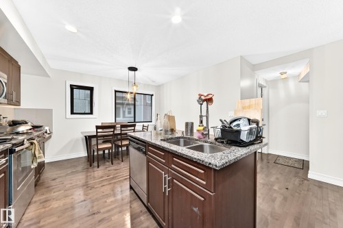 Kitchen featuring wood-finish flooring, recessed lighting, and a center island with a double basin sink - #146 655 Tamarack Rd Nw, Edmonton, AB 