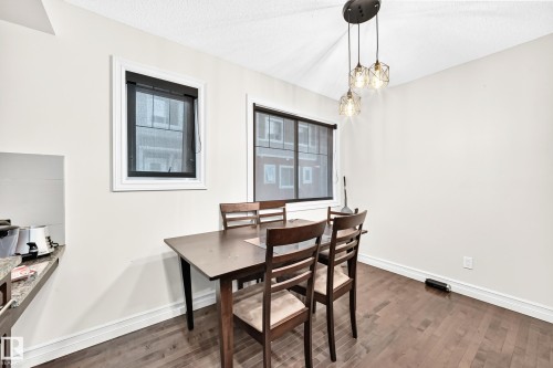 Wood-finish flooring, white walls, and a multi-light pendant fixture - #146 655 Tamarack Rd Nw, Edmonton, AB 