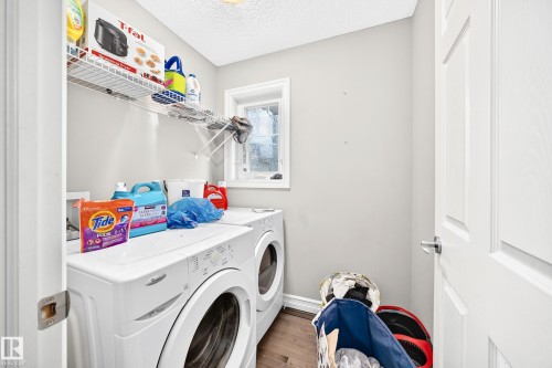 Laundry area with a built-in wire shelf, a window, and wood-finish flooring - #146 655 Tamarack Rd Nw, Edmonton, AB 