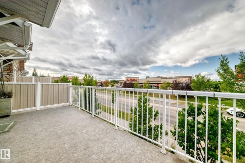Concrete balcony with white railing, privacy wall, and brick exterior accents - #146 655 Tamarack Rd Nw, Edmonton, AB 