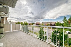 Concrete balcony with white railing, privacy wall, and brick exterior accents - 