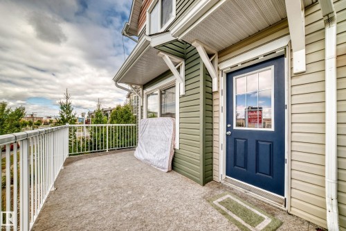 Concrete balcony with white railing, featuring a dark blue paneled door with glass inserts, and horizontal siding - #146 655 Tamarack Rd Nw, Edmonton, AB 