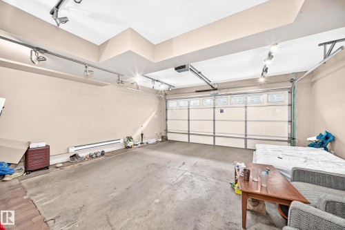 Attached two-car garage featuring track lighting, a garage door opener, and a cement floor - #146 655 Tamarack Rd Nw, Edmonton, AB 