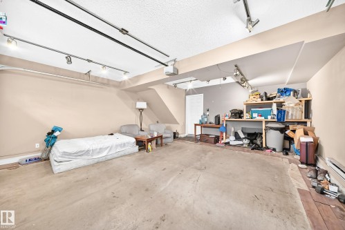 Concrete flooring, track lighting, built-in shelving, white door - #146 655 Tamarack Rd Nw, Edmonton, AB 
