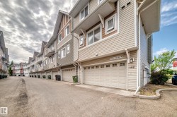 Siding exterior featuring a garage, white trim, and a gabled roofline - 