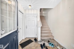 Entryway with patterned flooring, white paneled doors, and a carpeted staircase - 