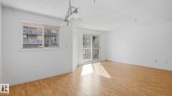 Wood-finish flooring, white walls, and a sliding glass door to an outdoor balcony - 