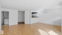 Bright living area with wood-finish flooring, white walls, and an overhead chandelier - 