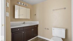 Bathroom featuring a dark wood finish vanity with integrated sink, white countertop, and a triple-door mirrored medicine cabinet - 