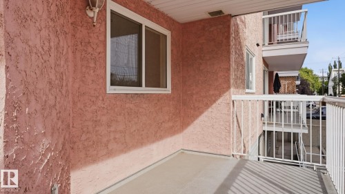 Private balcony with stucco exterior, white window frame, and white railings - #107 10153 117 St Nw, Edmonton, AB 