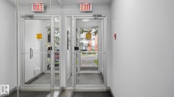 Double glass doors with aluminum frames, illuminated "EXIT" signs, and grey floor mats - 