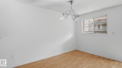 Recessed window with white frame, light wood-finish flooring, white walls, and a multi-bulb ceiling fixture - 