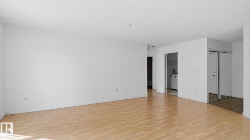 Hardwood-style flooring throughout, white walls, and a recessed laundry area - #107 10153 117 St Nw, Edmonton, AB 