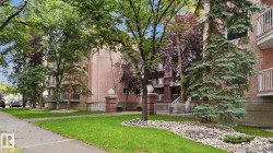 Building exterior with multiple balconies, mature trees, and a landscaped rock garden - 