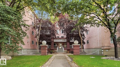 Multi-story building featuring a textured pink exterior and prominent entry staircase - #107 10153 117 St Nw, Edmonton, AB 