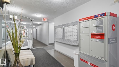 Corridor with recessed lighting, wall-mounted mailboxes, and a parcel locker - #107 10153 117 St Nw, Edmonton, AB 