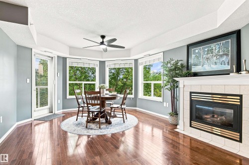 Hardwood flooring, fireplace with tile surround, multiple windows, ceiling fan, and access to an outdoor area - #432 6703 172 St Nw, Edmonton, AB 