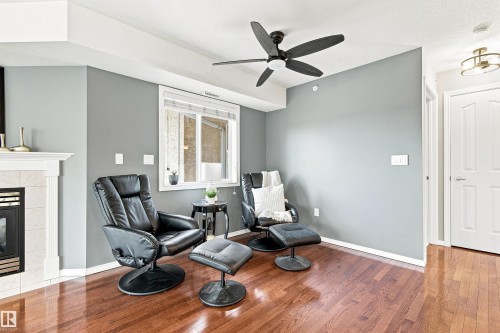 Hardwood flooring, white trim, overhead lighting, ceiling fan, and a gas fireplace with a mantel - #432 6703 172 St Nw, Edmonton, AB 