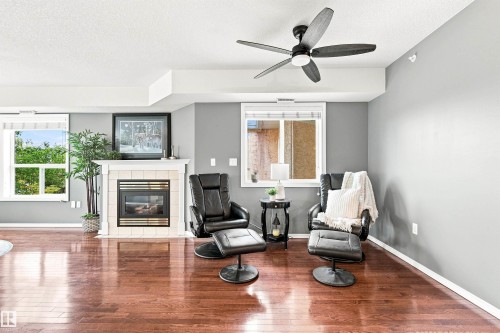 Hardwood flooring, fireplace with tile surround and mantel, ceiling fan, recessed lighting, and multiple windows - #432 6703 172 St Nw, Edmonton, AB 