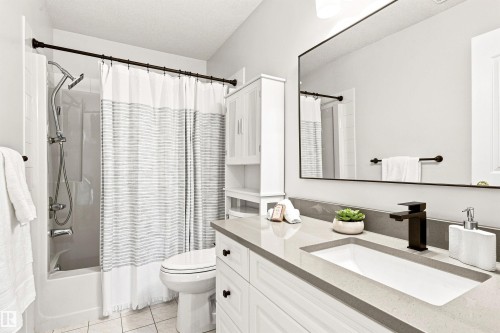 Built-in bathtub with shower, vanity with integrated sink, stone-finish countertop, and wall-mounted mirror - #432 6703 172 St Nw, Edmonton, AB 