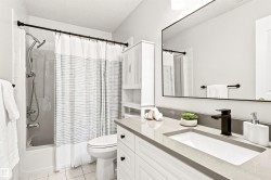Built-in bathtub with shower, vanity with integrated sink, stone-finish countertop, and wall-mounted mirror - 