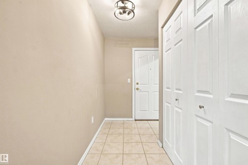 Entryway featuring tile flooring, a paneled door, and bi-fold closet doors - #432 6703 172 St Nw, Edmonton, AB 