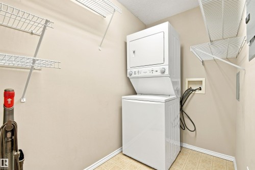 Laundry area featuring a stackable washer and dryer, wire shelving, and neutral wall paint - #432 6703 172 St Nw, Edmonton, AB 
