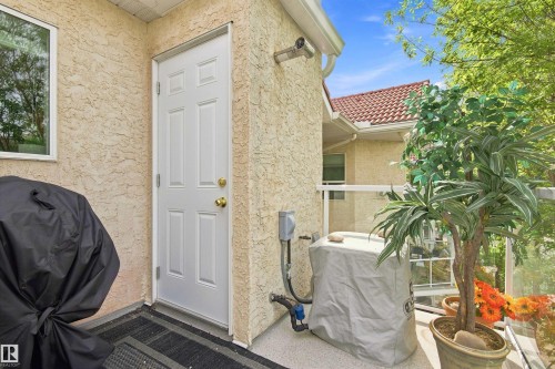 Balcony with stucco exterior, a white paneled door, and a glass-paneled railing - #432 6703 172 St Nw, Edmonton, AB 