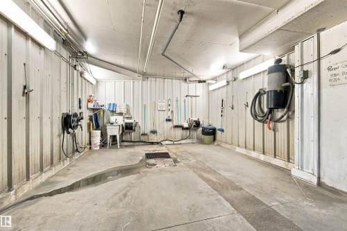 Concrete flooring with integrated drainage system, corrugated metal wall panels, and overhead fluorescent lighting fixtures - #432 6703 172 St Nw, Edmonton, AB 