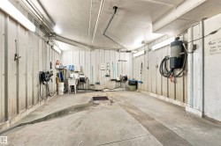 Concrete flooring with integrated drainage system, corrugated metal wall panels, and overhead fluorescent lighting fixtures - 