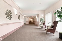 Carpeted hallway featuring wall sconces, decorative wall art, and vertical blinds on windows - 