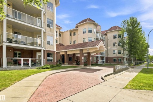Multi-story building featuring balconies with glass railings, a covered entry, and a paved drive - #432 6703 172 St Nw, Edmonton, AB 